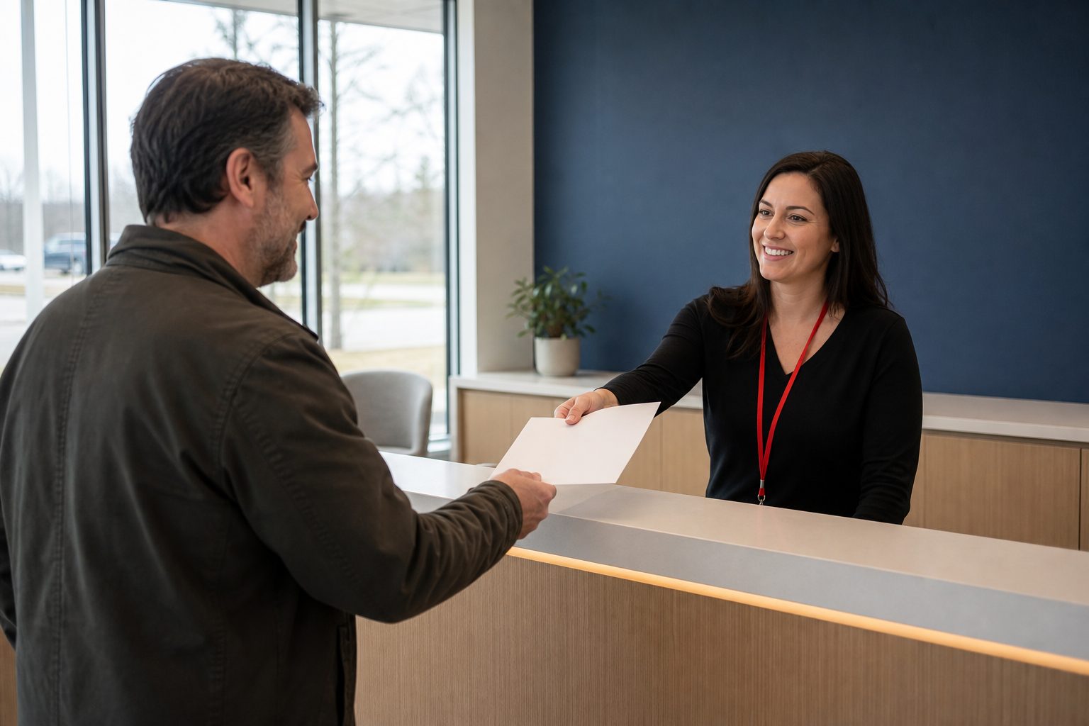 An F1 coordinator at the front desk handing a client their appointment confirmation.