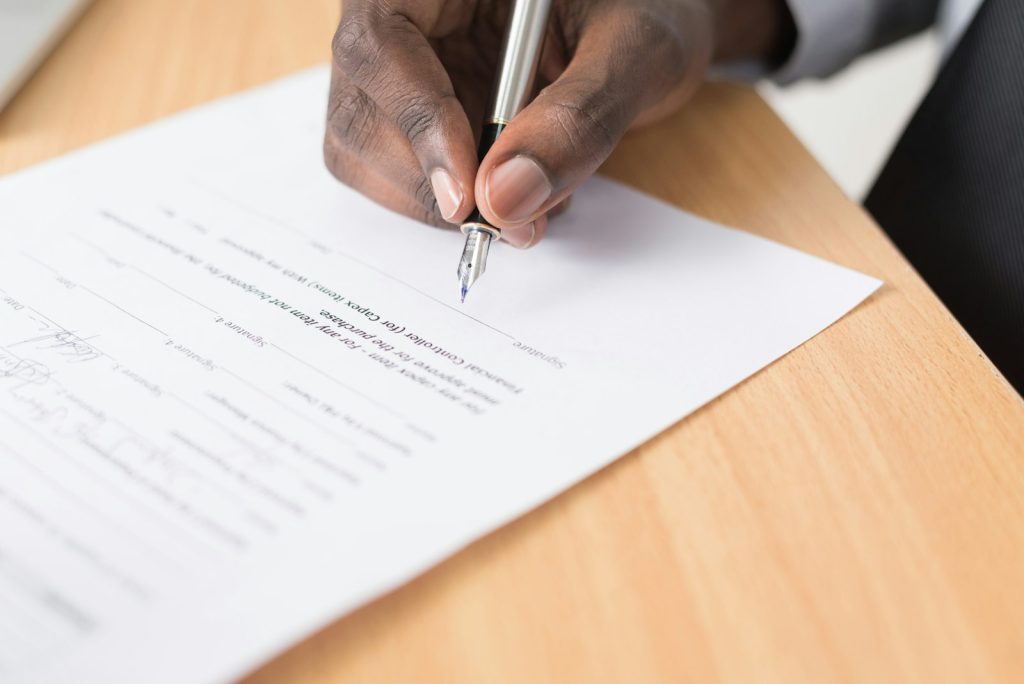 A hand signing an official document at a desk